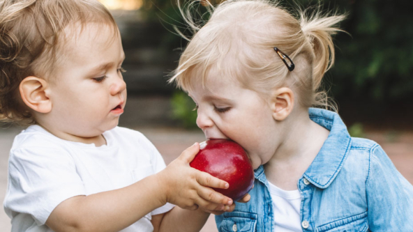 Two children sharing an apple